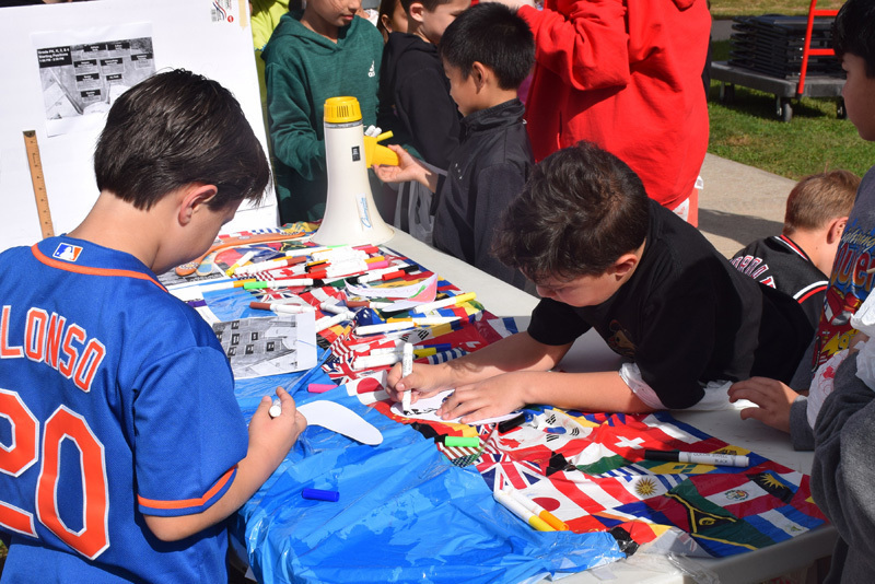students gather around a table of flags