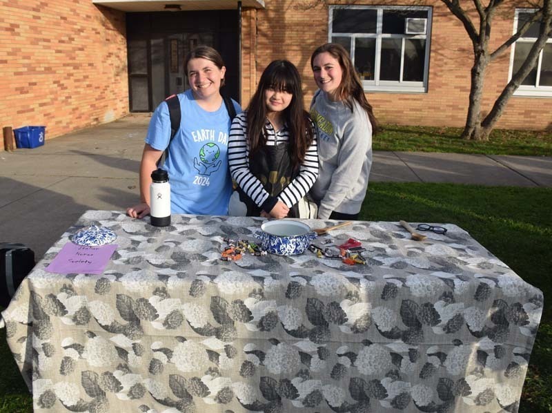 Photo of students dressed up in Halloween costumes outside in front of their tables with candy.