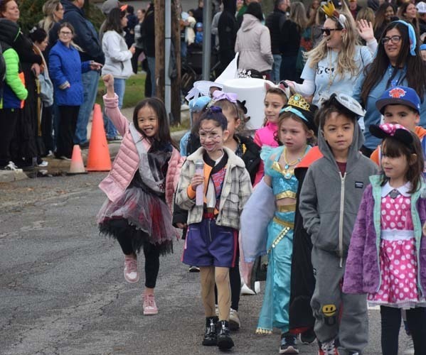 Students marching on the street while wearing Halloween costumes.