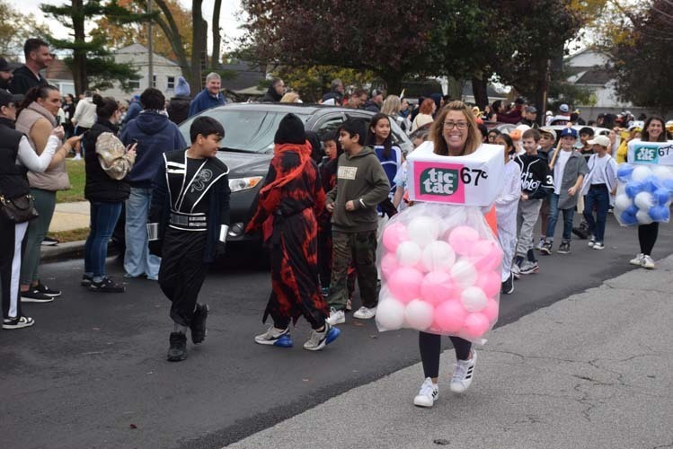 Students marching on the street while wearing Halloween costumes.