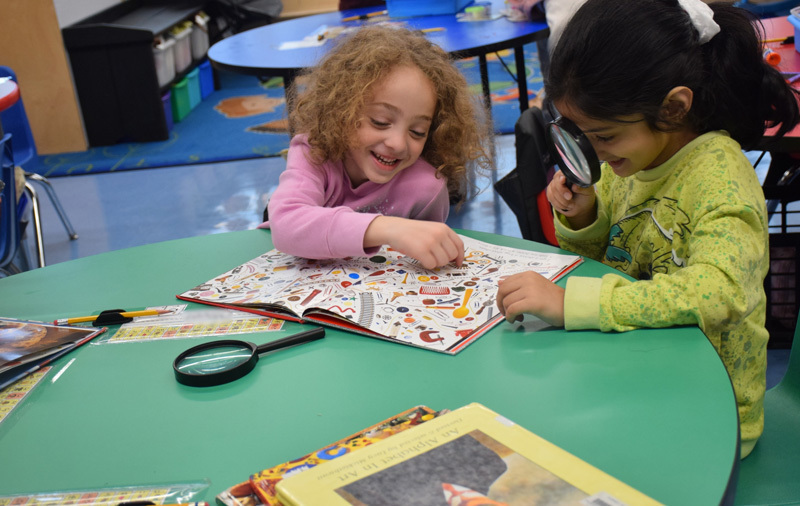  sitting with at a round table covered with educational materials and crafts, conveying a cheerful learning atmosphere.