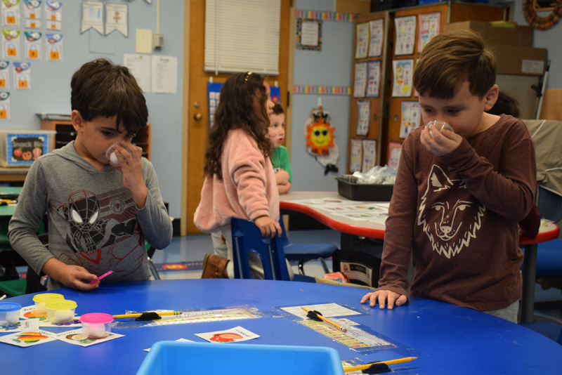  sitting with at a round table covered with educational materials and crafts, conveying a cheerful learning atmosphere.