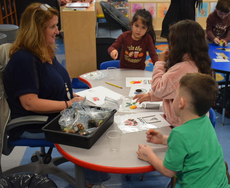  sitting with at a round table covered with educational materials and crafts, conveying a cheerful learning atmosphere.