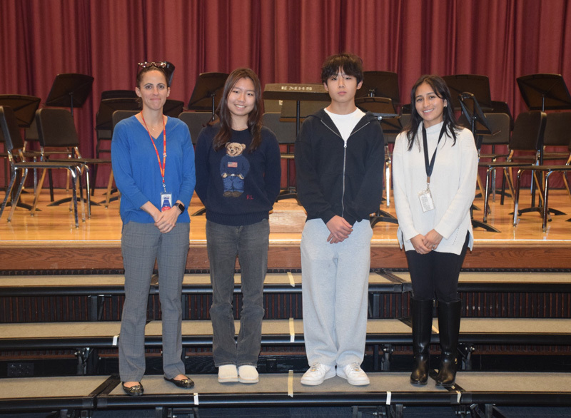 A diverse group of teenagers and adults stand on risers against a purple curtain backdrop, smiling warmly, conveying a sense of camaraderie and community.