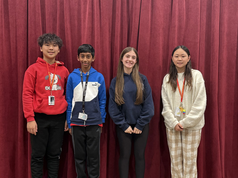 A diverse group of teenagers and adults stand on risers against a purple curtain backdrop, smiling warmly, conveying a sense of camaraderie and community.