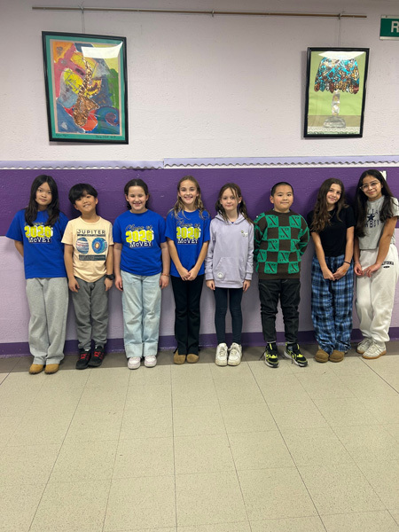group of smiling children stand in a school hallway
