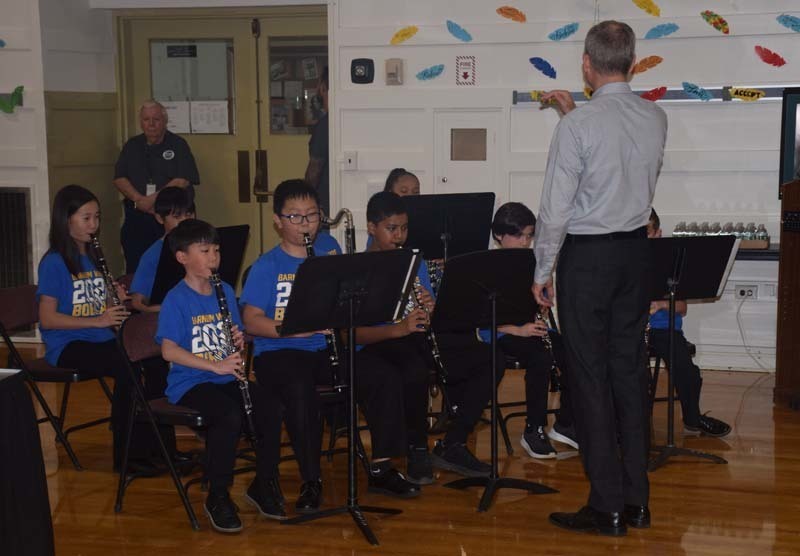 Students sitting in chairs playing their instruments.
