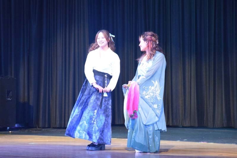 Photo of students wearing traditional, colorful dresses from their home country while dancing.