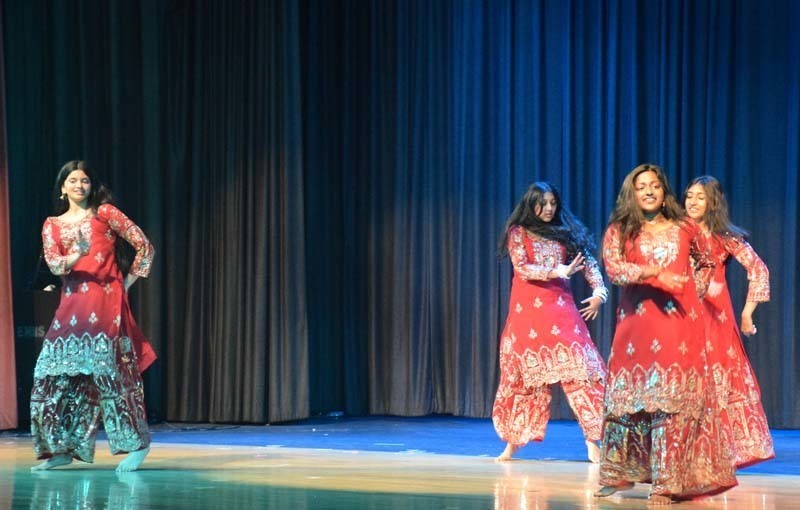 Photo of students wearing traditional, colorful dresses from their home country while dancing.
