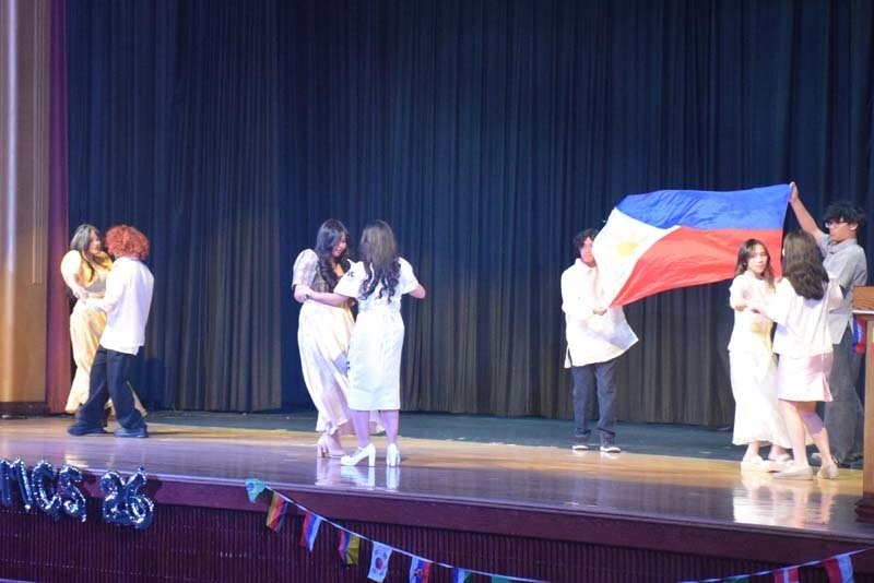 Photo of students wearing traditional, colorful dresses from their home country while dancing.