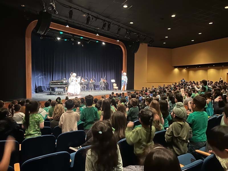 “Meeting Mozart” concert being performed on a stage while students watch