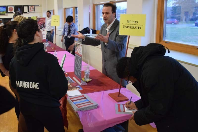 People talking at a college fair booth in the gym