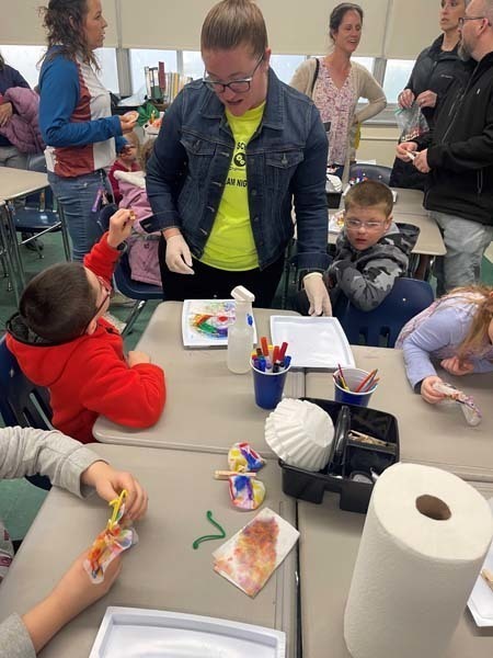 An adult helping students with their projects An adult helping students with their projects