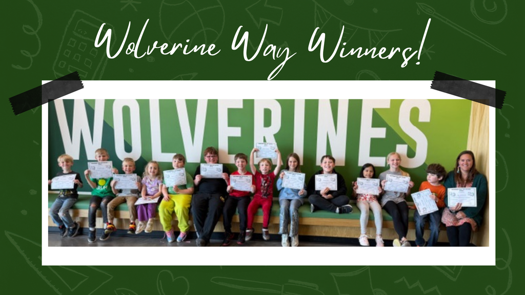 A group of elementary students sitting on a bench in front of the large "WOLVERINE" wall, holding their Wolverine Way certificates