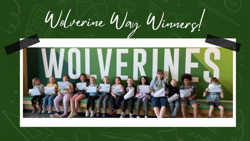 Group of elementary students sitting in front of a "Wolverines" sign proudly displaying their certificates