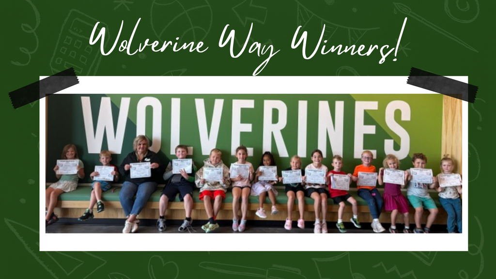 Students smiling in front of a "wolverine" sign, holding their certificates
