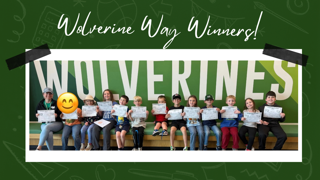 Students smiling in front of a "wolverine" sign, holding their certificates