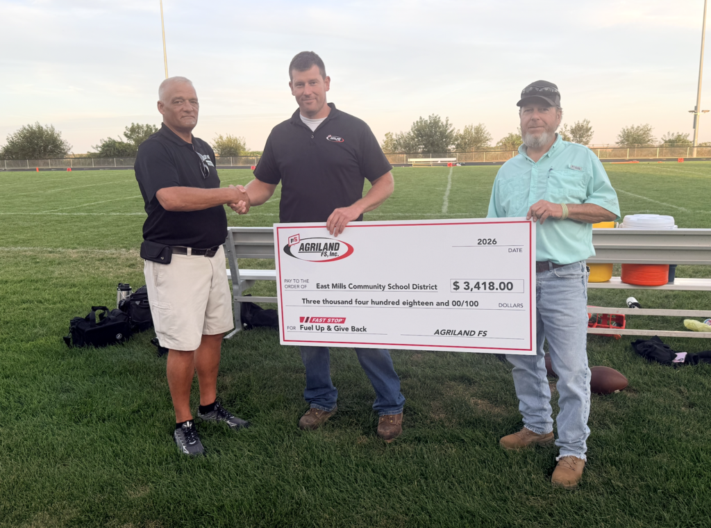 Mr. Brown shaking hands with Agriland location manager, as they present East Mills with a ceremonial check of $3,418