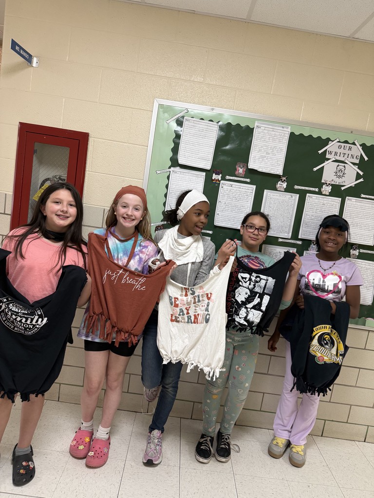 Students showing their reusable bags they made using old t-shirts.