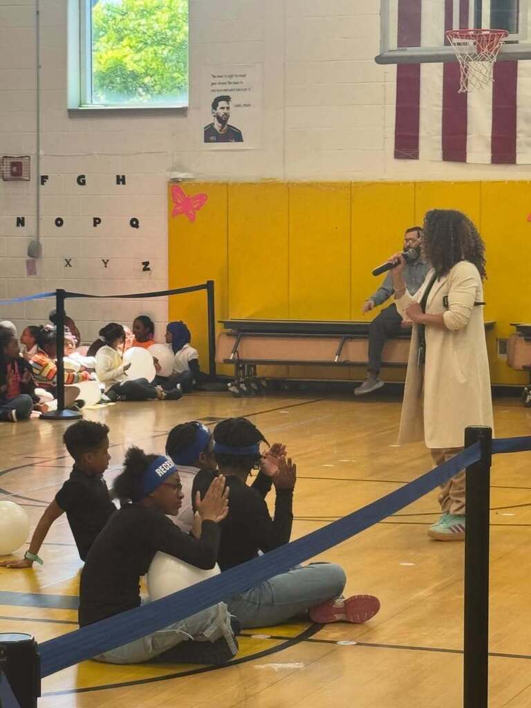 Principal of Cicely Tyson Elementary is speaking to students in the gymnasium