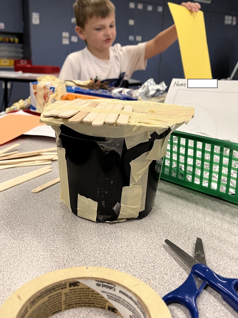 Student desigining a structure with class supplies