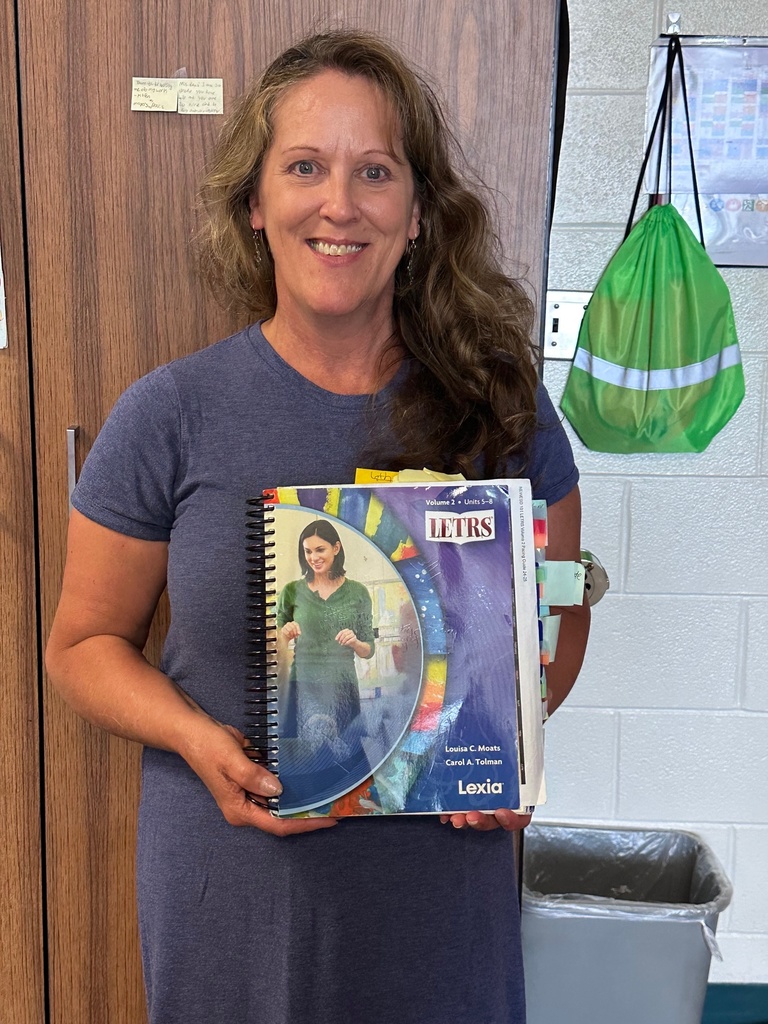 a woman standing and displaying a curriculum book