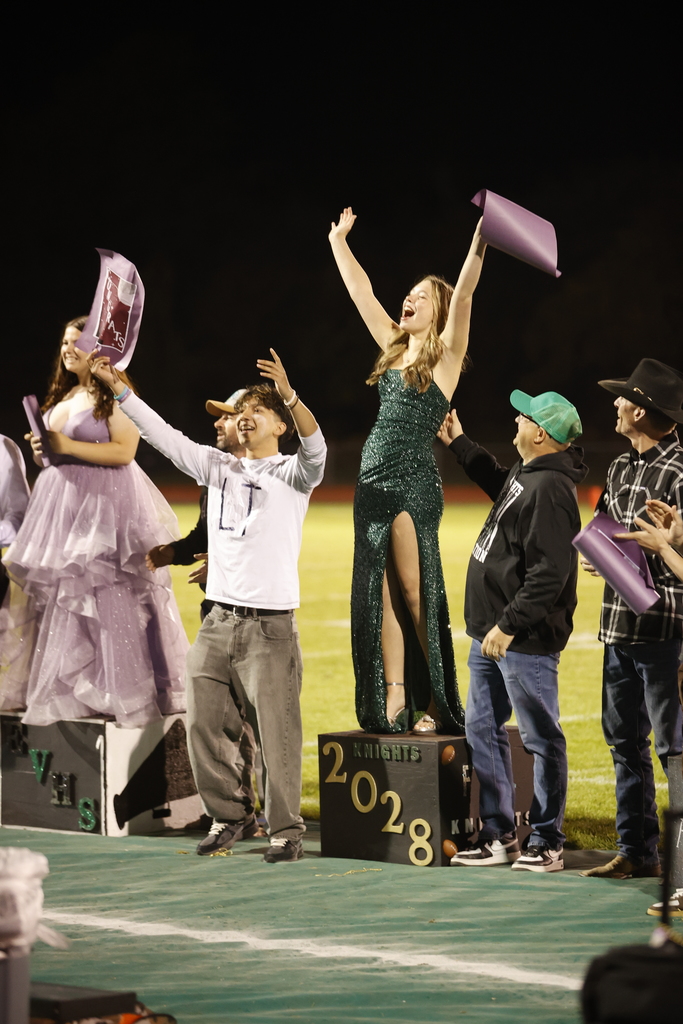 students and adults dressed formally on podiums holding congrats posters and cheering