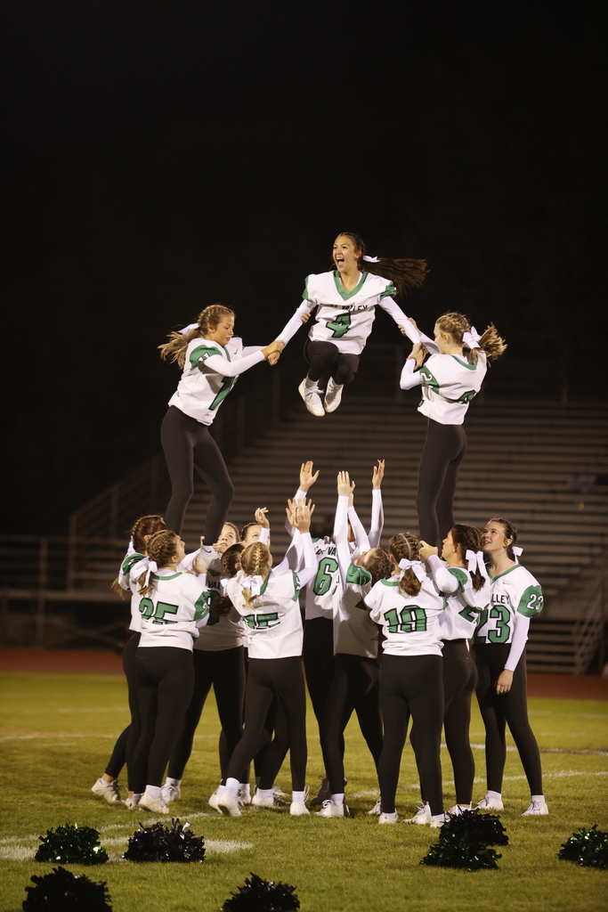 a group of girl cheerleaders on a football field performing