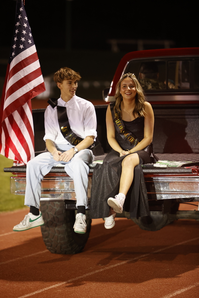 a boy and a girl in formal attire riding in the back of a truck bed