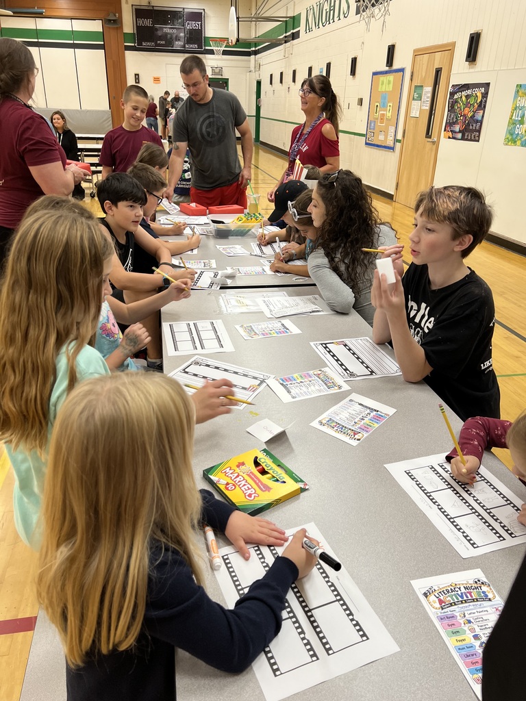 A group of students sit at tables, drawing and coloring in a classroom. Some use markers.