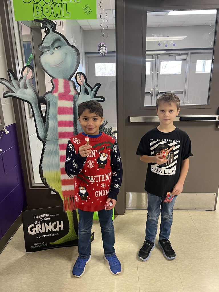 two students posing with small santas in front of the grinch