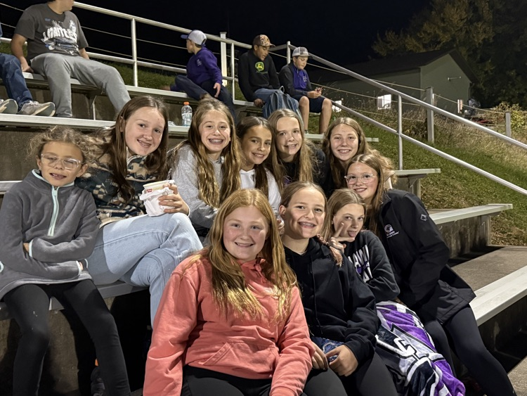 group of kids sitting on bleachers smiling at the camera