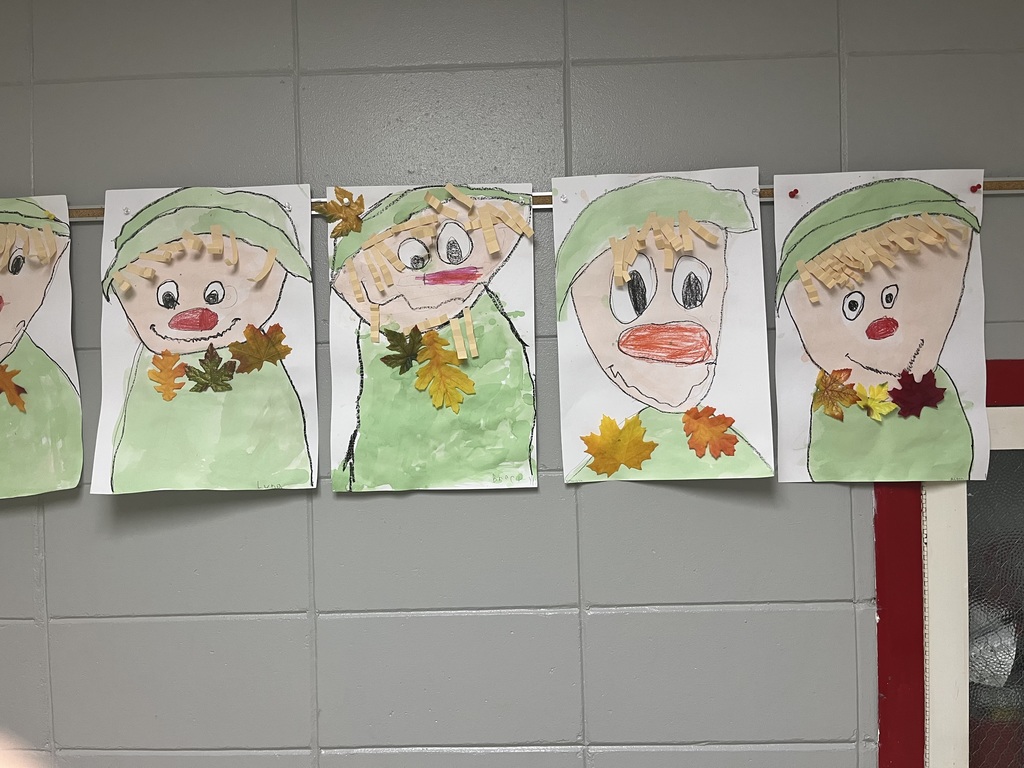 Art projects created by elementary students hanging on a grey wall 