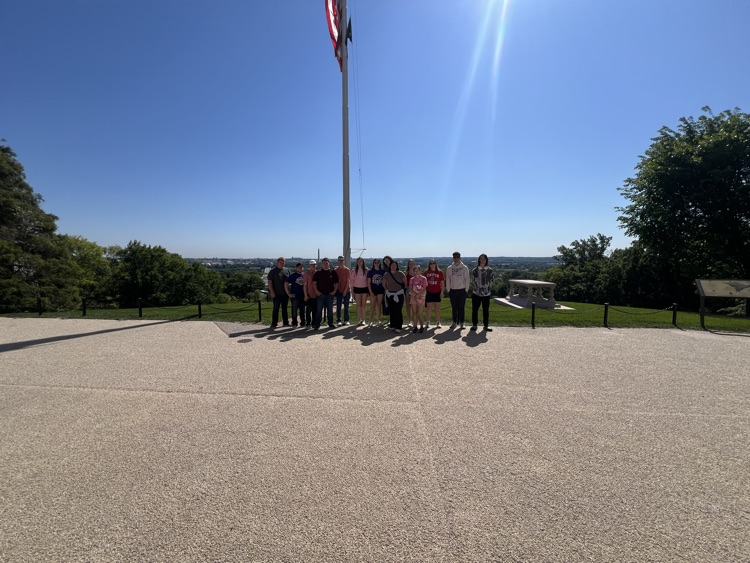 students facing away from the sun with a flagpole and Washington DC behind them