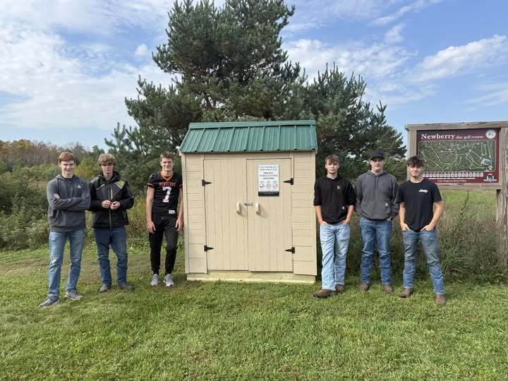 six students standing near a shed they built to donate