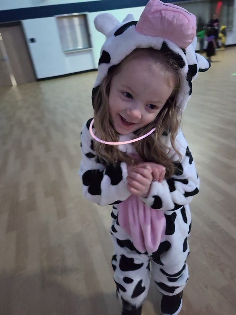 A grinning preschooler shows off her fuzzy cow costume. 