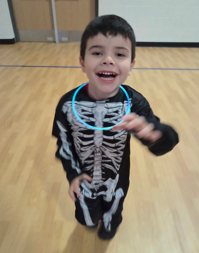 A smiling preschooler dances in a skeleton costume. 