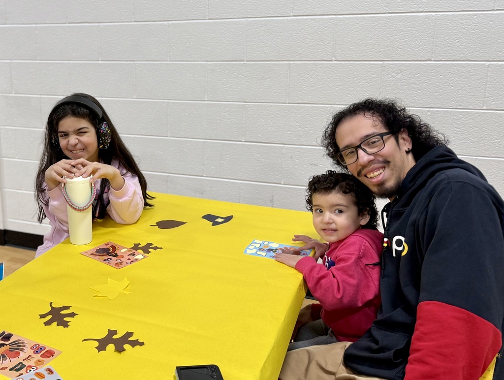 A student smiles and a toddler sits on a parent's lap.