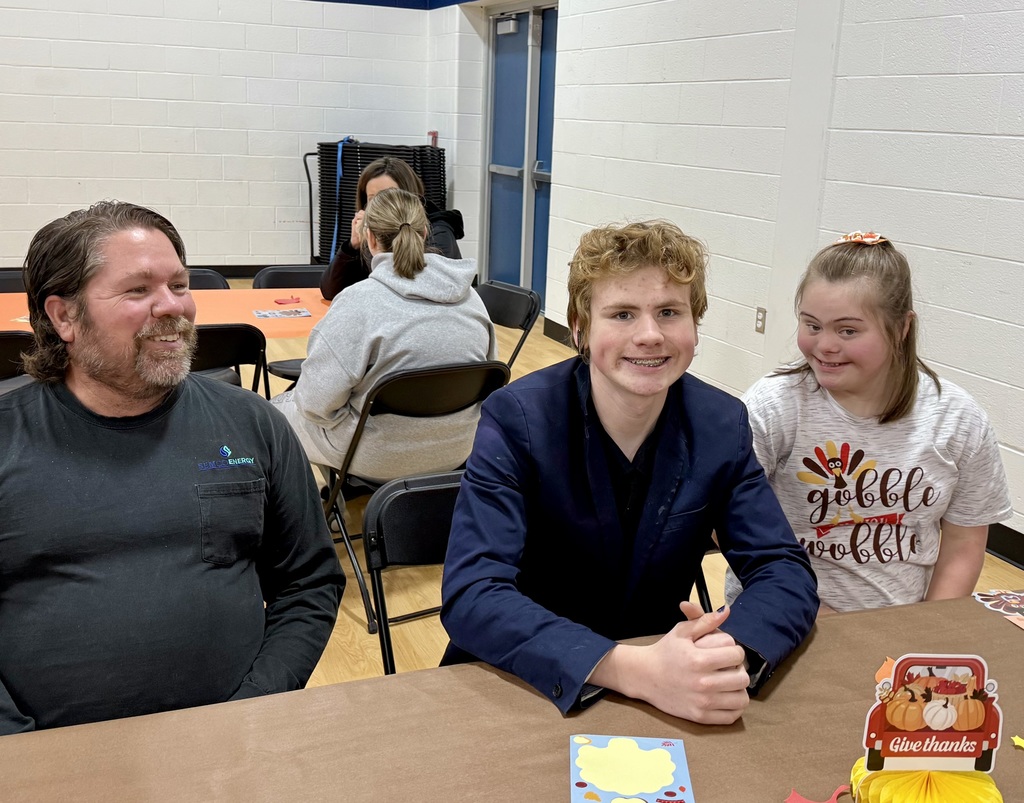 An adult and two students smile for the camera.