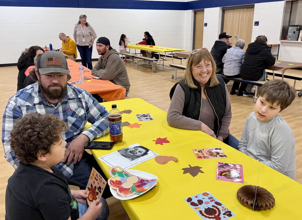 Two adults and two students sit at a festively decorated table.