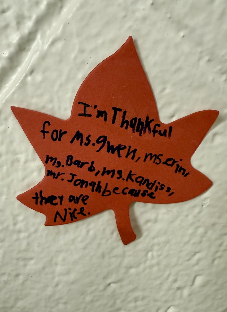 A bright orange construction paper leaf. The handwriting reads: "I'm thankful for Ms. Gwen, Ms. Erin, Ms. Barb, Ms. Kandiss, Mr. Jonah because they are nice.