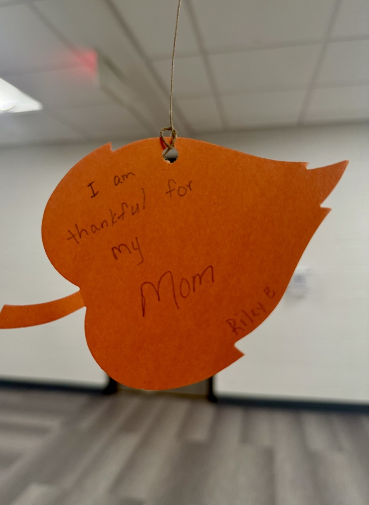A bright orange construction paper leaf. The handwriting reads: "I am thankful for my mom."