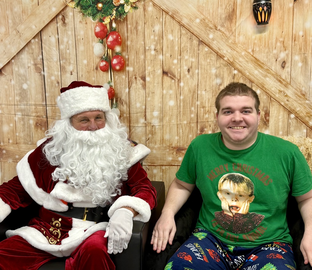 Santa and a smiling student pose for the camera. The student has a "Home Alone" t-shirt.
