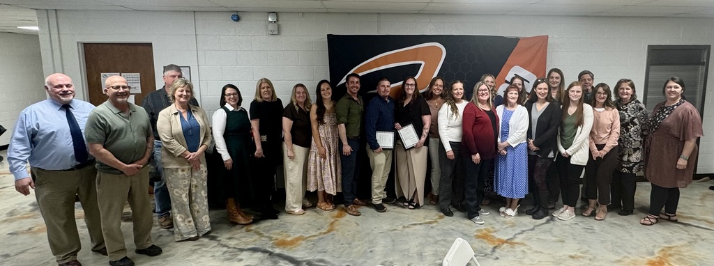 employees of the year gathered around a black and orange rudyard area schools banner for employee of the year dinner awards
