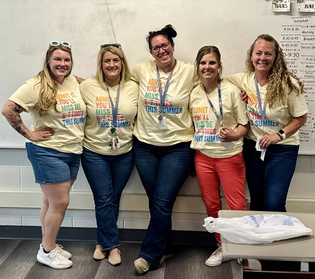 A group smiling staff pose smile in matching summer t-shirts. 