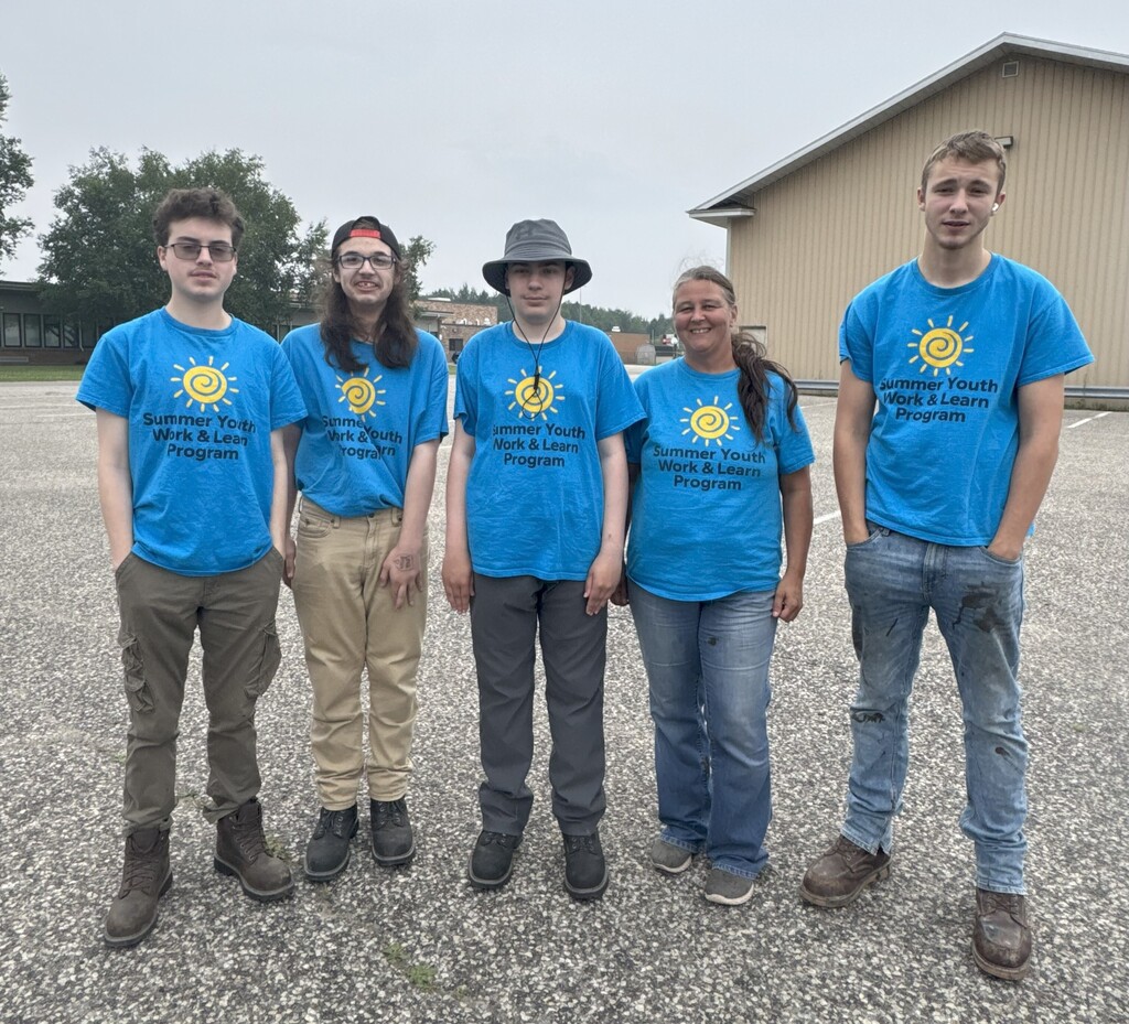 5 people in bright blue Summer Youth Work & Learn shirts pose in a line for the camera.