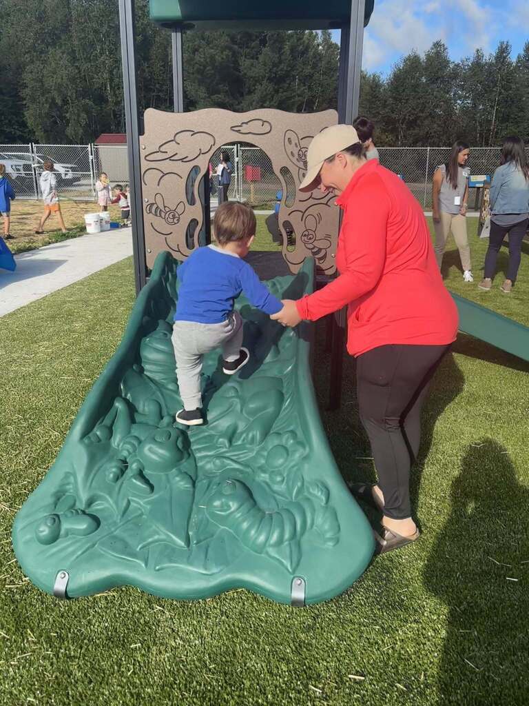Child and adult playing on playground toy