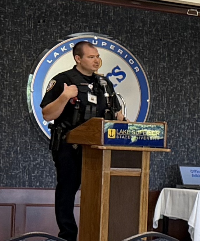 Officer at podium speaking to students