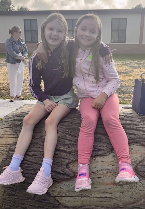 two girls sitting on the log crawl tunnel