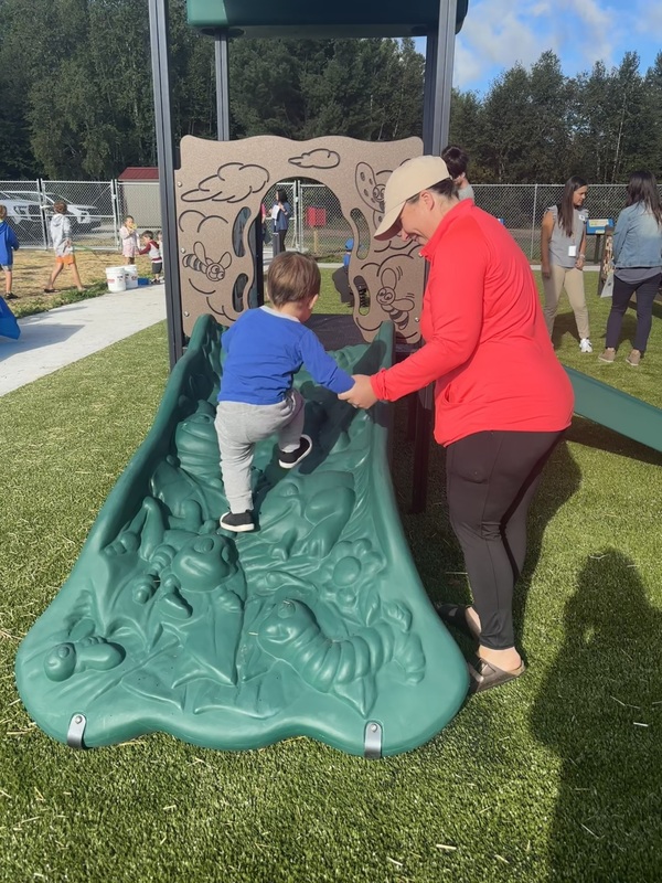 child climbing the toddler structure with mom helping him